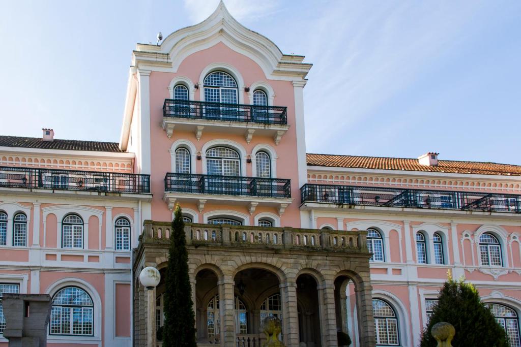 un grand bâtiment rose avec des balcons en haut dans l'établissement INATEL Palace S.Pedro Do Sul, à Termas de São Pedro do Sul