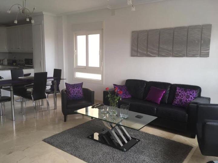 Una sala de estar con un sofá negro y una mesa. en Jumilla III, en Orihuela Costa