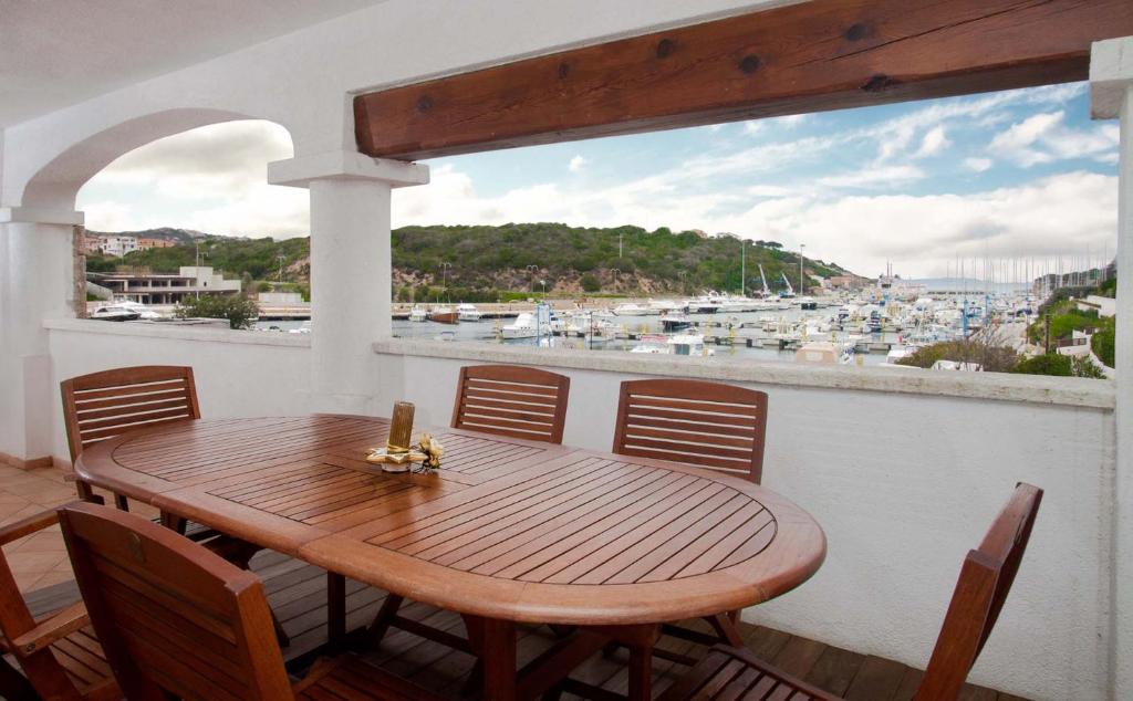 un tavolo in legno su un balcone con vista sul porto di Trilocale Vignamarina a Santa Teresa di Gallura