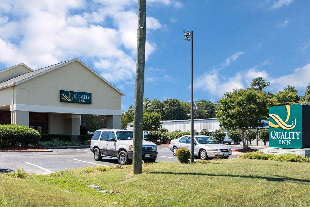 a building with two cars parked in a parking lot at Quality Inn Warsaw near Rappahannock River in Warsaw