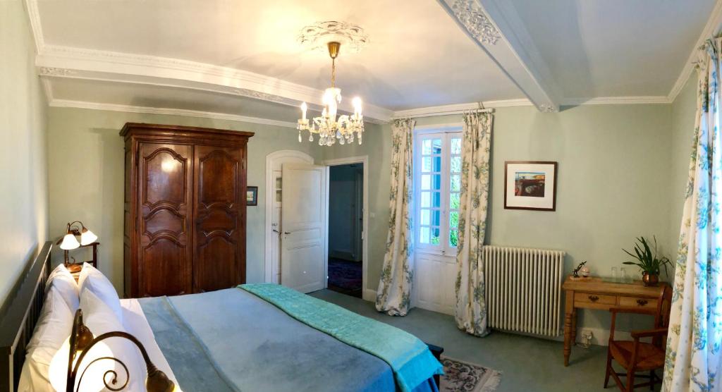 a bedroom with a bed and a chandelier at Le Chevalier Noir in Cordes-sur-Ciel