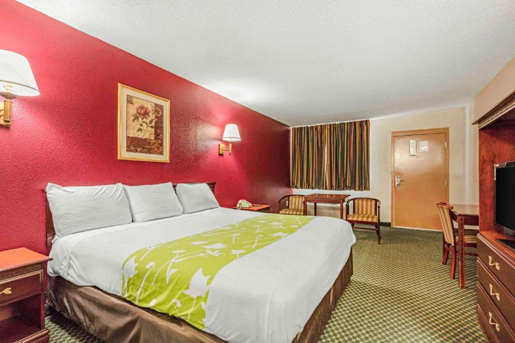 a large bed in a room with a red wall at Rodeway Inn Prattville I-65 in Prattville