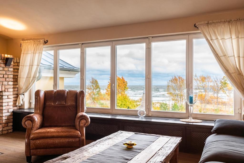 uma sala de estar com um sofá, uma mesa e janelas em Villa am Strand em Ahlbeck