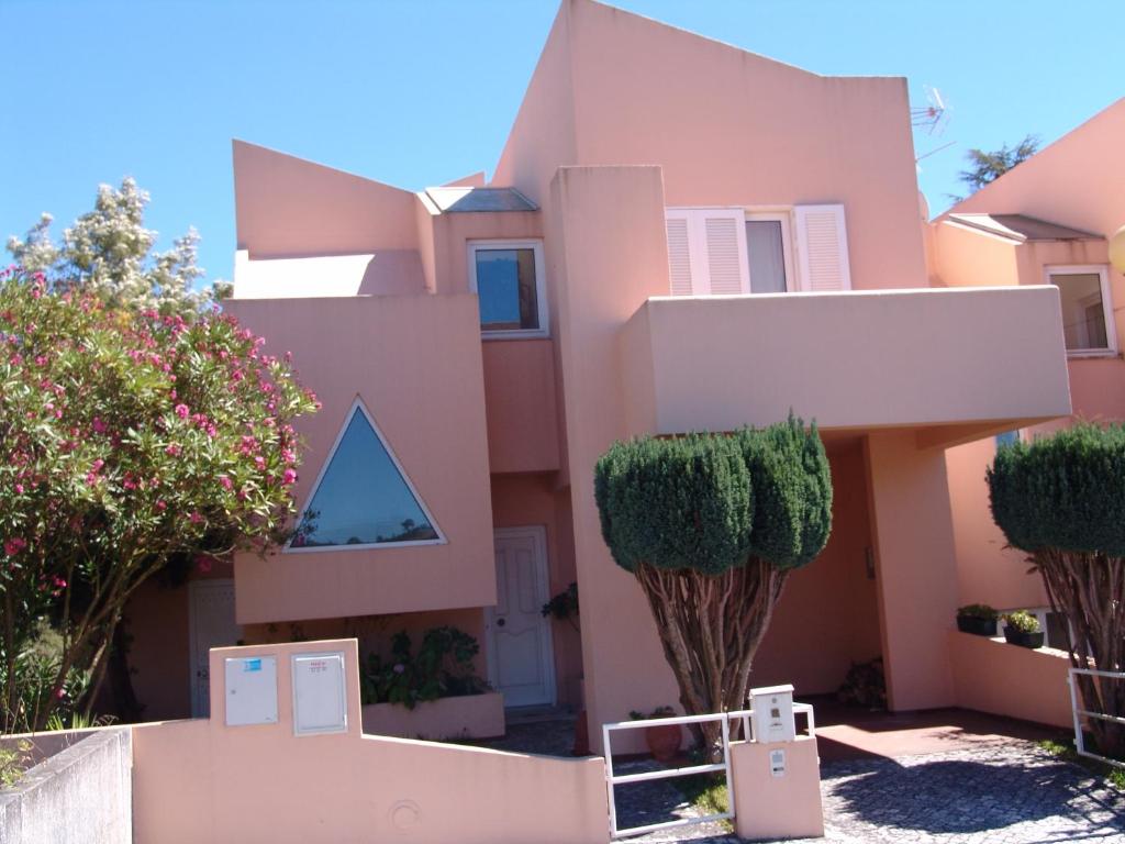 uma casa cor-de-rosa com árvores à frente. em Lugar de Óbidos em Óbidos