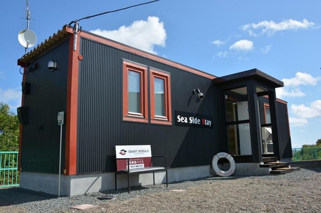 Une petite maison noire sur un tas de gravier dans l'établissement Sea Side Stay / Vacation STAY 1785, à Abashiri