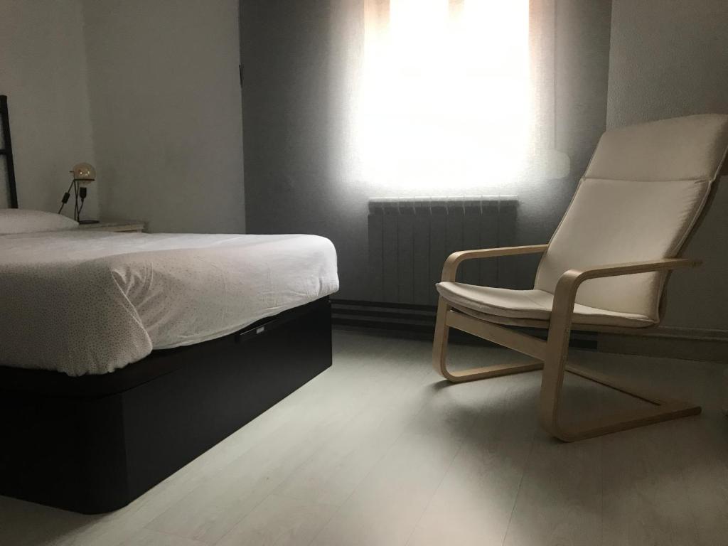 a bedroom with a bed and a chair next to a window at Apartamento Casa Edurne in Valladolid