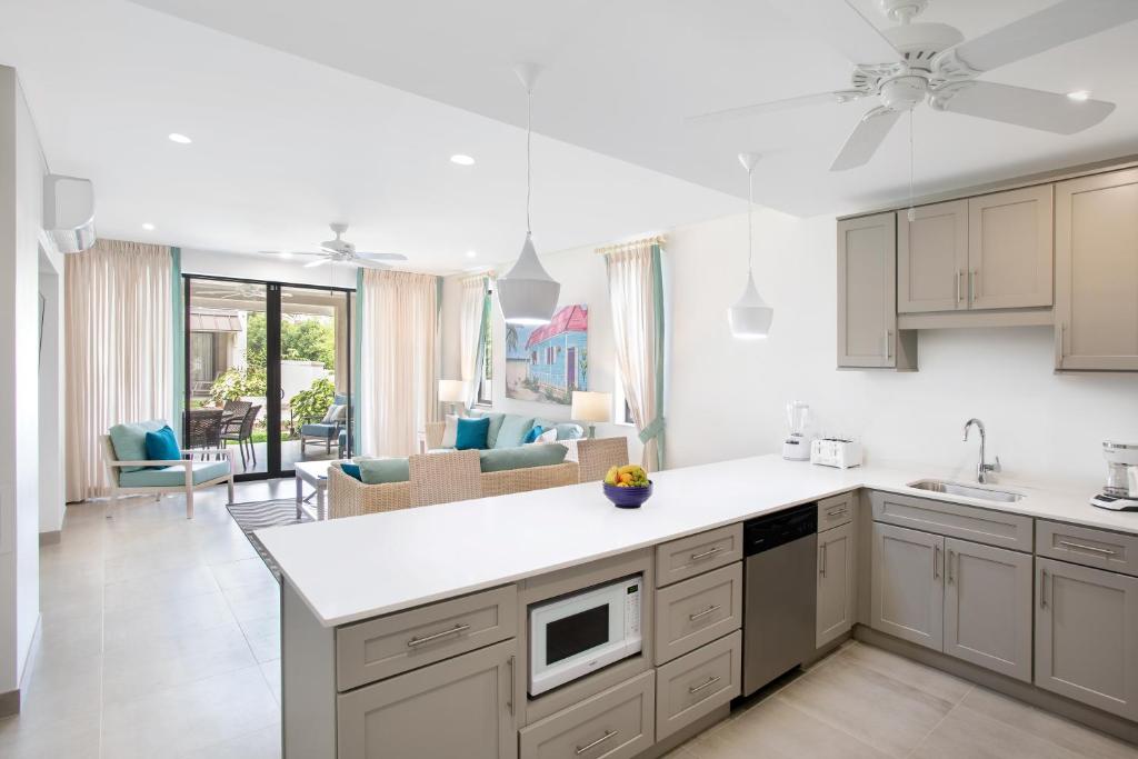 a kitchen with white cabinets and a living room at Beach View Hotel in Saint James
