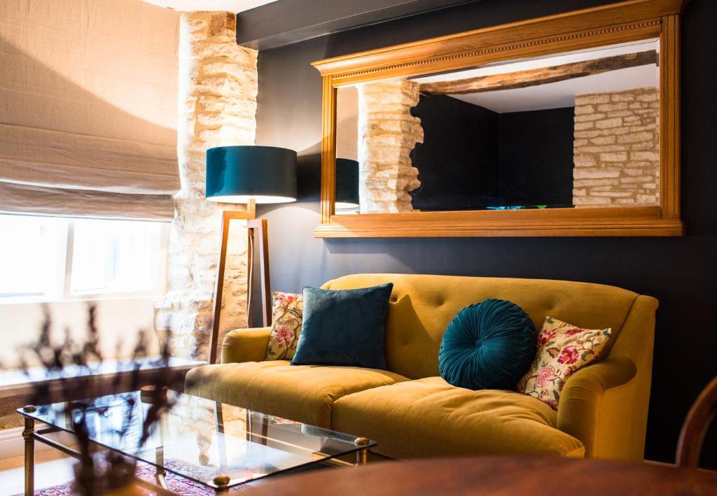 a living room with a yellow couch and a mirror at Cotswold Place in Cirencester