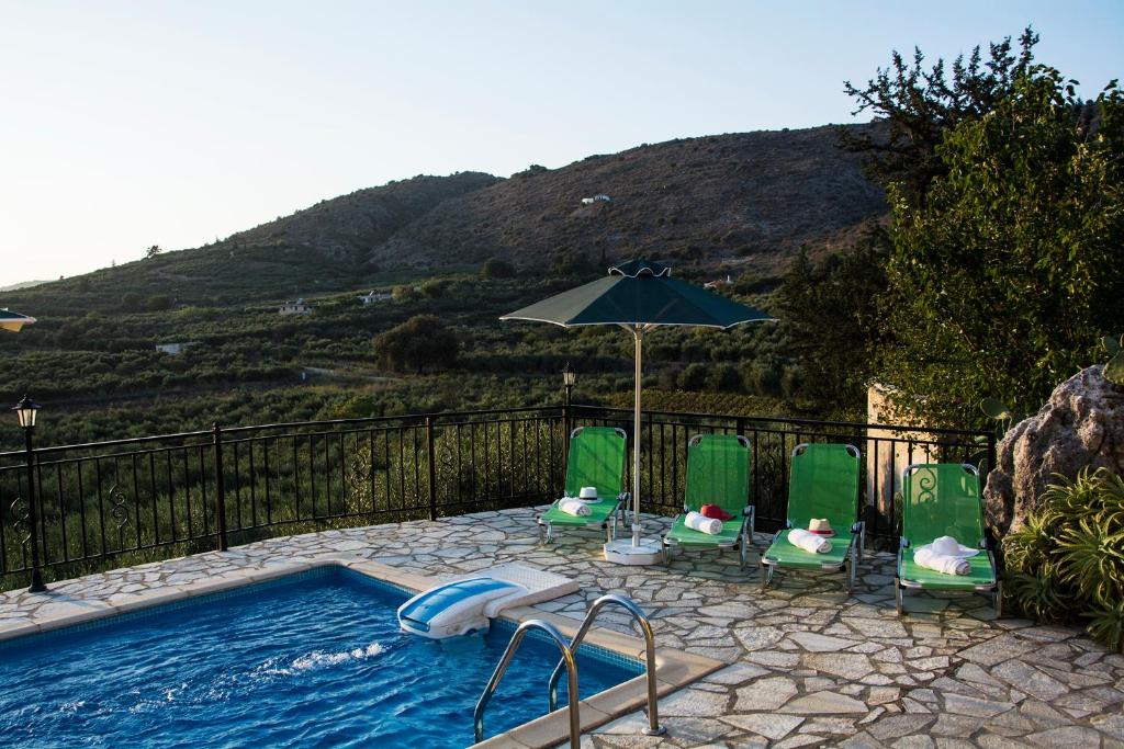 a swimming pool with lawn chairs and an umbrella at Villa Manos in Kalamitsi Amygdali