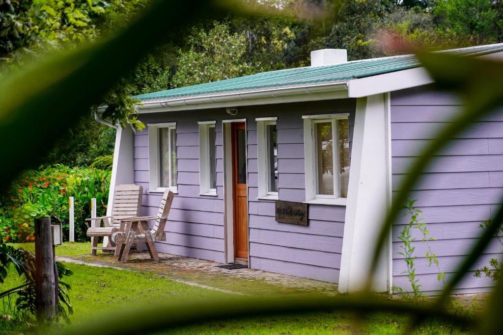 Cabaña púrpura con mesa y silla en Natures Way Bushbuck Cottage, en The Crags