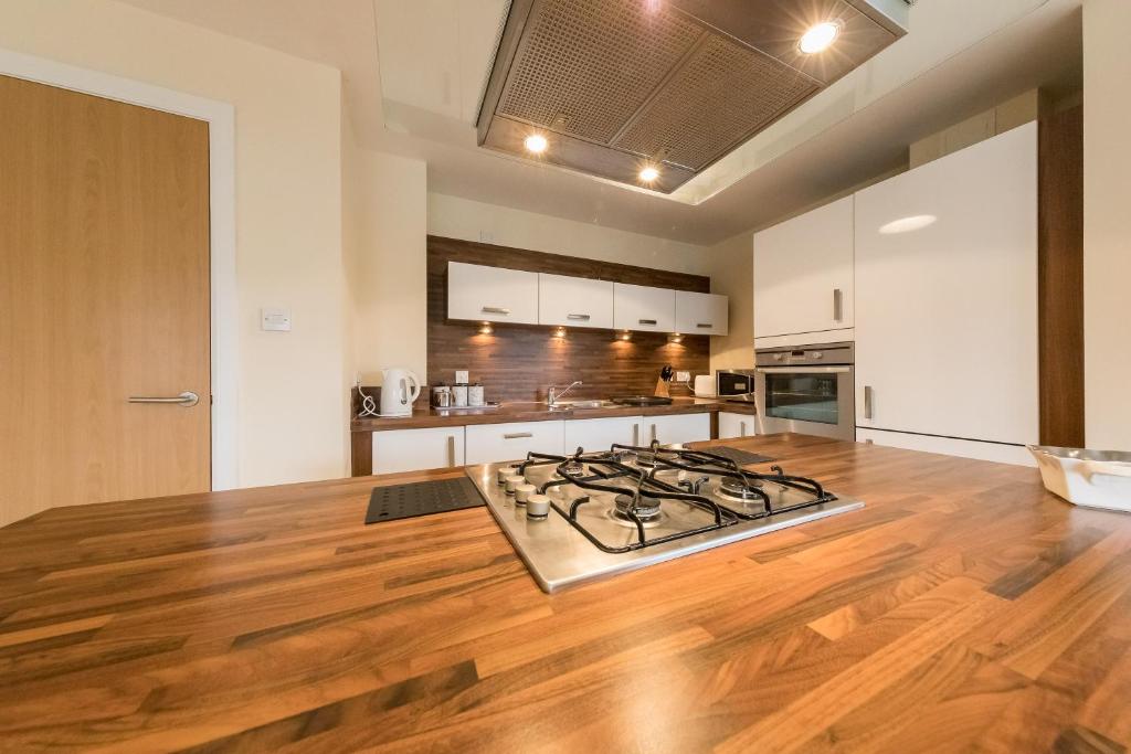 a kitchen with a stove and a wooden floor at The Broch, 1st Floor, Luxurious City Centre Apartment in Perth