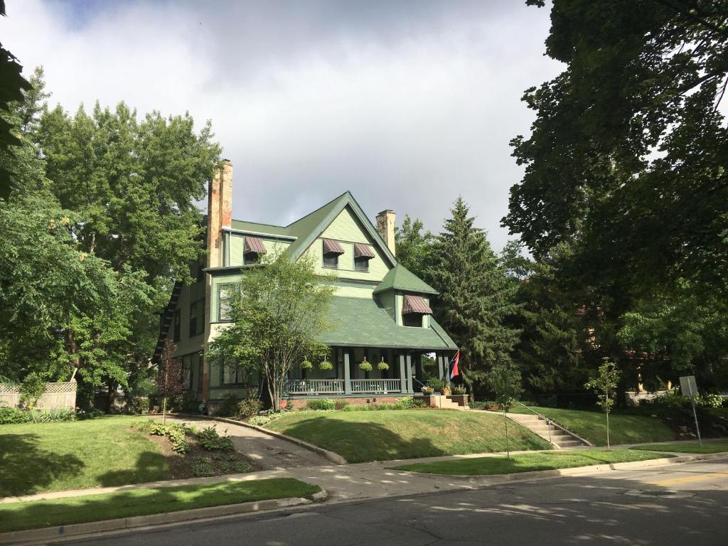 a green house on a hill with a street at The Parsonage Inn B&B in Grand Rapids