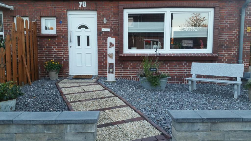 ein Backsteinhaus mit einer weißen Tür und einer Bank in der Unterkunft Ferienhaus Wilhelmshaven Voslapp 78 in Wilhelmshaven