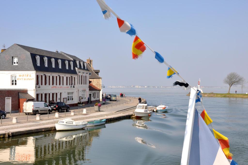 een boot in het water naast een dok met boten bij Hotel du Port et des Bains in Saint-Valery-sur-Somme