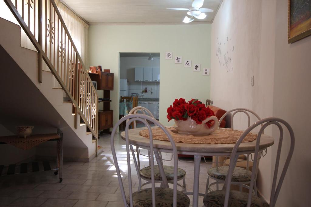 a dining room table with chairs and a vase of flowers on it at Casa Olímpia Thermas in Olímpia