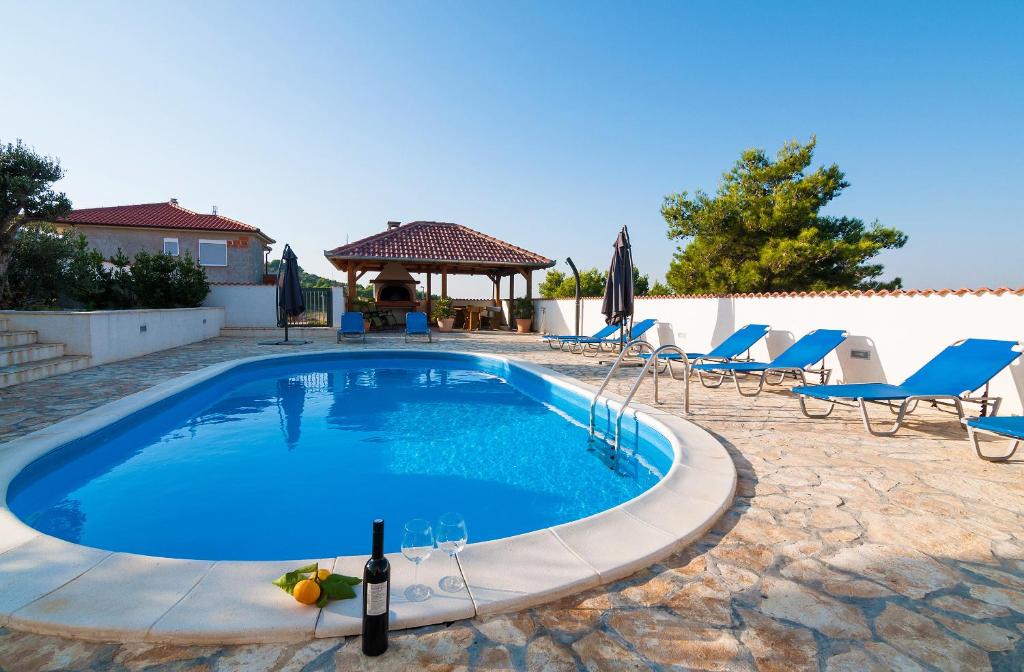 a swimming pool with chairs and a bottle of wine at Villa Branka with pool in Drage