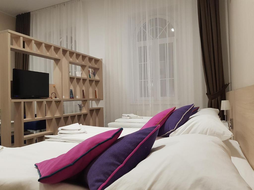 um quarto com duas camas com almofadas e uma televisão em Hotel Story em Sarajevo