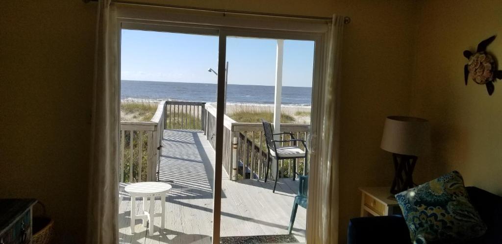a door to a balcony with a view of the ocean at Blue Crab Cove in Oak Island