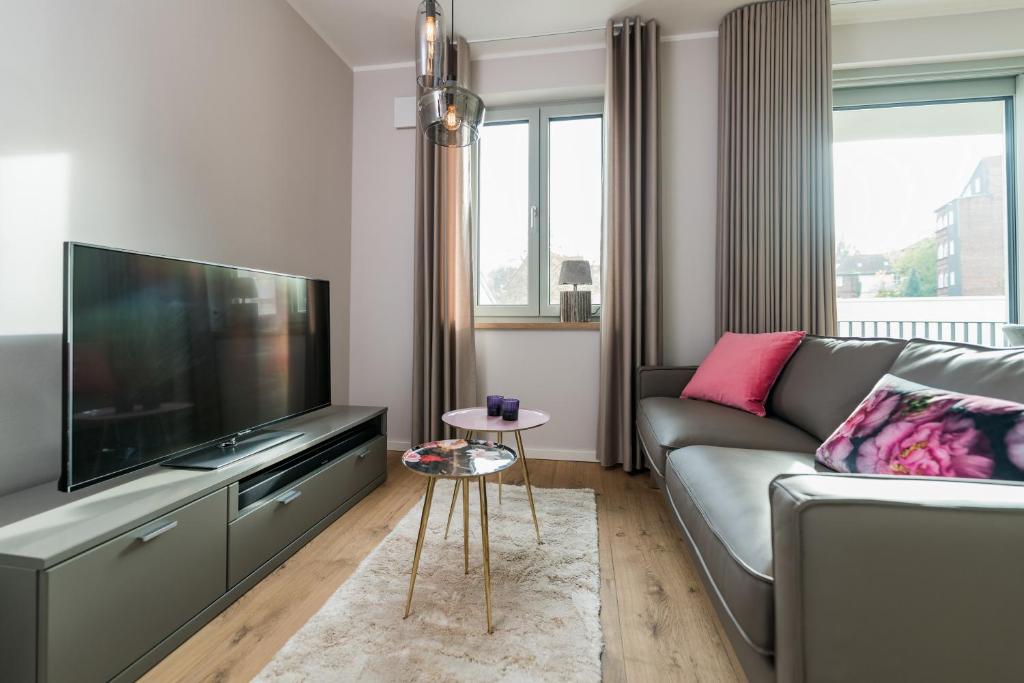 a living room with a couch and a flat screen tv at Suites MITTE - Aparthotel in Eisenach