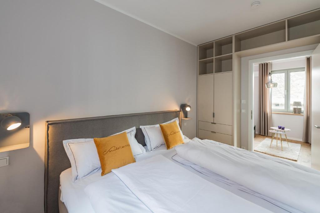 a bedroom with a large white bed with yellow pillows at Suites MITTE - Aparthotel in Eisenach