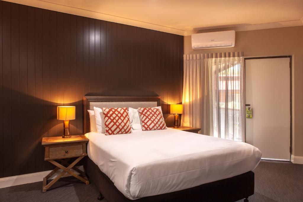 a bedroom with a large bed and two lamps on tables at Nightcap at Archer Hotel in Nowra