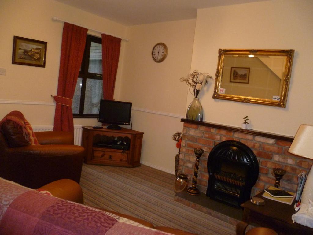 a living room with a fireplace and a mirror at Gilmore House in Ardglass