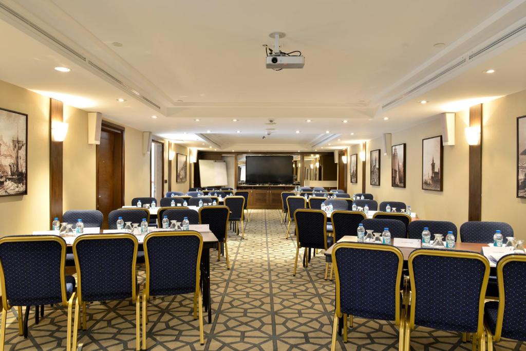 a conference room with tables and chairs and a screen at Nidya Hotel Galataport in Istanbul