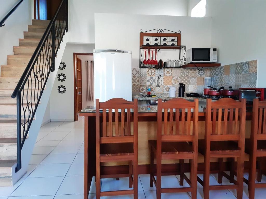 una cocina con encimera y algunas sillas de madera en Casa Lagoa de Geribá - 2 quartos, en Búzios