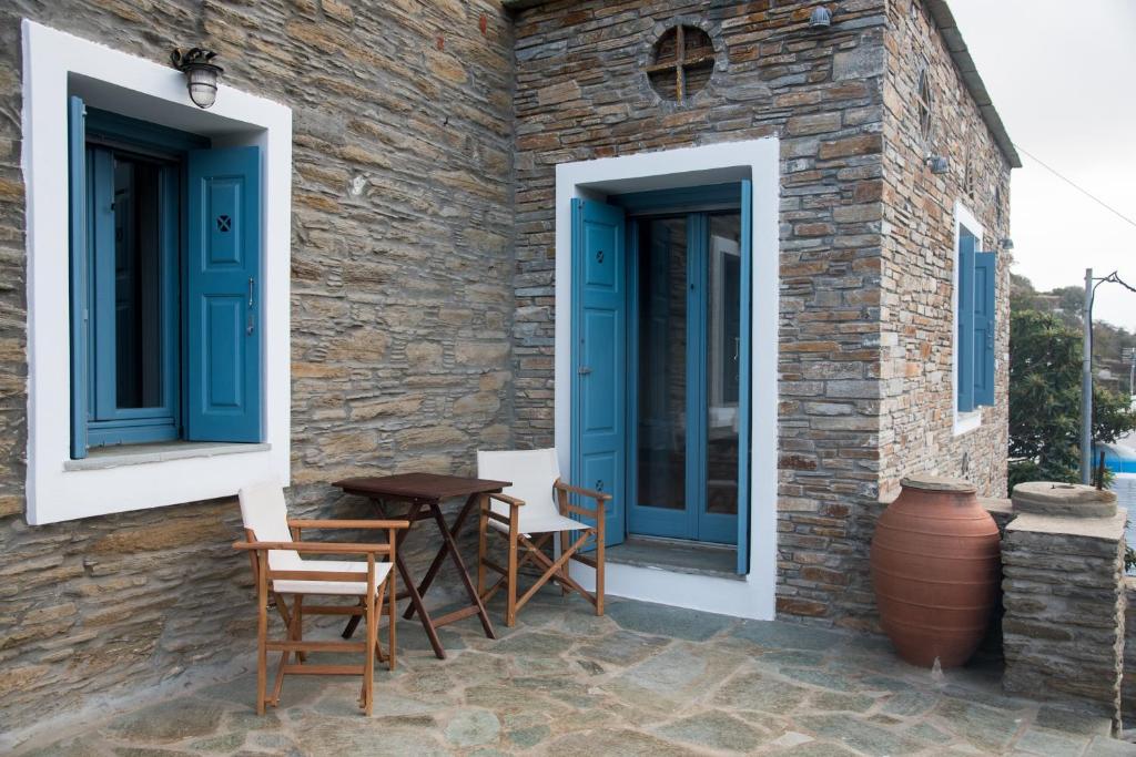 a stone house with blue windows and a table and chairs at Petra Traditional House in Episkopión