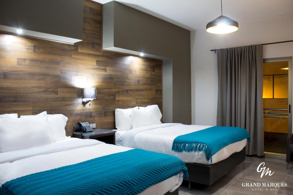 a hotel room with two beds and a wooden wall at Grand Marques in San Juan de los Lagos