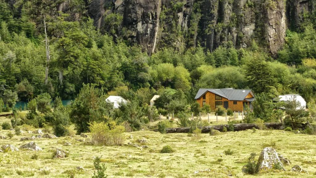 una cabaña de madera en un campo en una montaña en Matapiojo Lodge, en Futaleufú