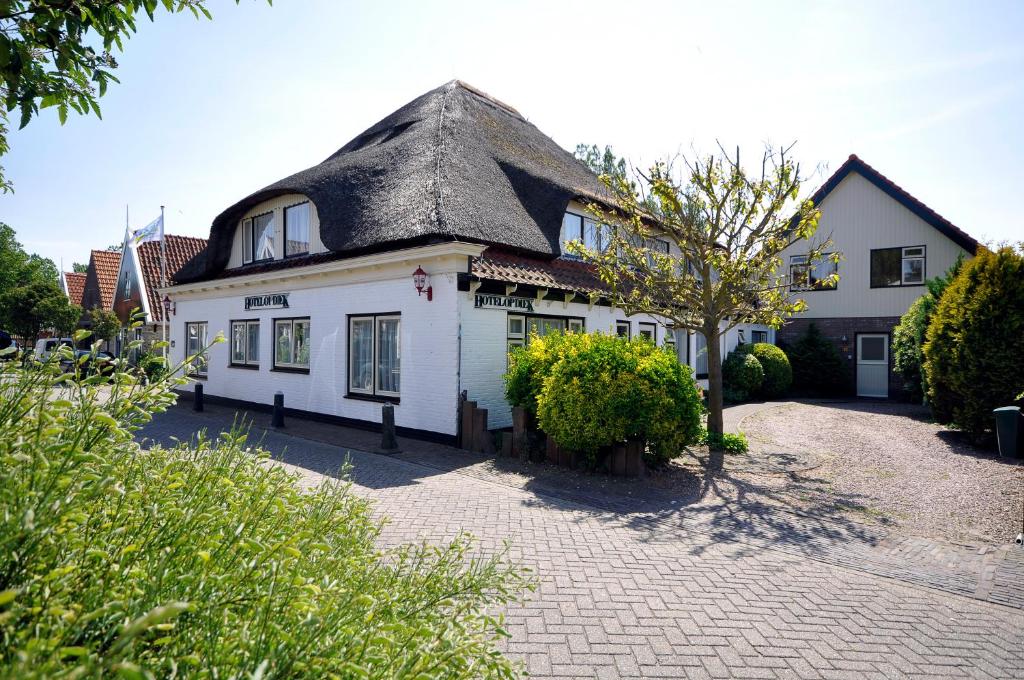een groot wit huis met een rieten dak bij Hotel Op Diek in Den Hoorn