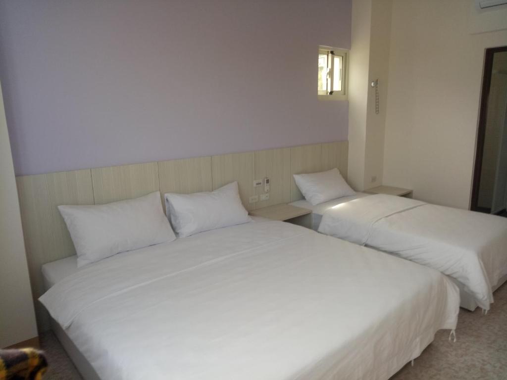 dos camas blancas sentadas una al lado de la otra en una habitación en 馬祖北竿達露岸海景民宿 可電洽, en Beigan