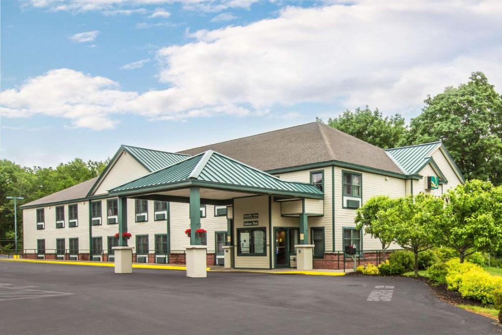 a large white building with a green roof at Econo Lodge Glens Falls - Lake George in Glens Falls