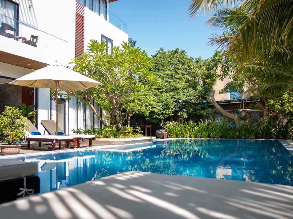 ein Pool mit Sonnenschirm neben einem Gebäude in der Unterkunft Hoi An Reverie Villas in Hoi An