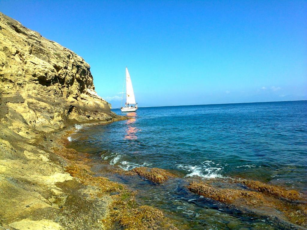 a sail boat in the ocean with a rocky shore at Villa Mira Capri in Procida