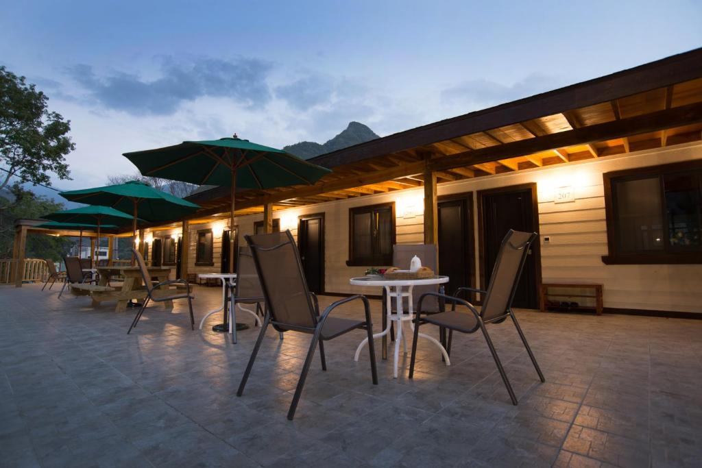 eine Terrasse mit Tischen, Stühlen und Sonnenschirmen in der Unterkunft Tang Zhimei Hot Spring in Taian