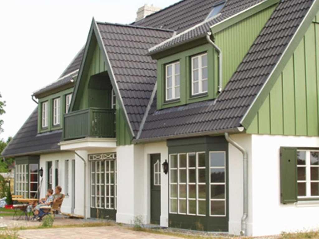 a green and white house with people sitting at Haus am Achterwasser Whg "Klabautermann" in Ueckeritz