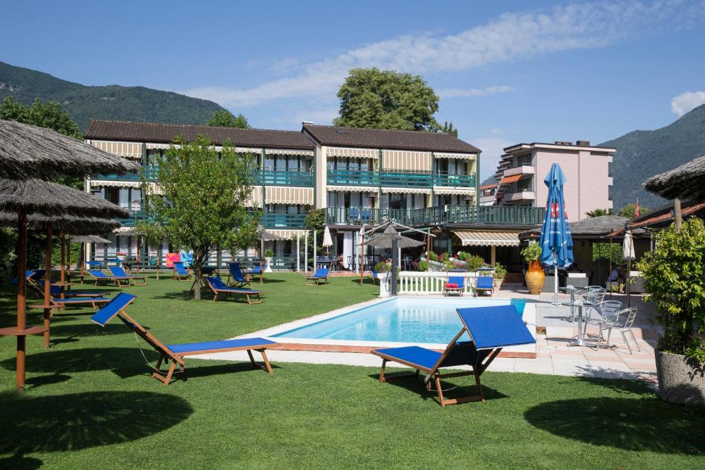 een resort met een zwembad en stoelen en een gebouw bij Hotel Tiziana in Losone