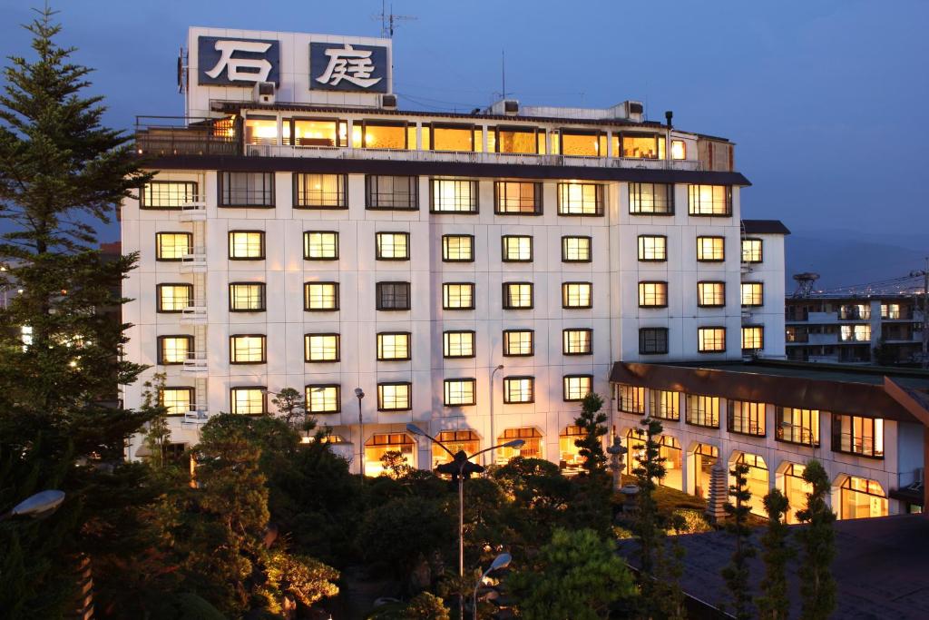 een groot wit gebouw met verlichting aan bij Hotel Sekitei in Fuefuki