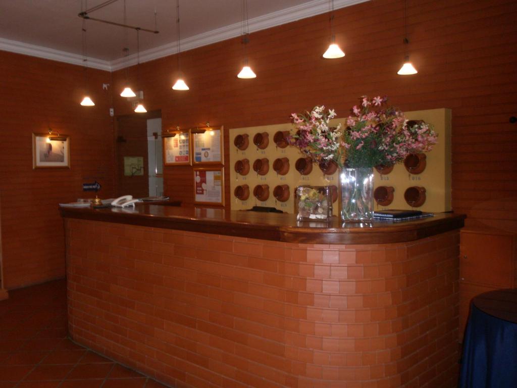 a bar with a vase of flowers on a brick wall at Hotel Passagem do Sol in Moura