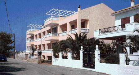 a large pink building with palm trees in front of it at Hotel Marialena in Archangelos