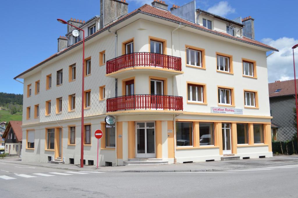 Un grand bâtiment blanc avec des balcons rouges se trouve dans une rue. dans l'établissement Hôtel Timgad, à Gérardmer