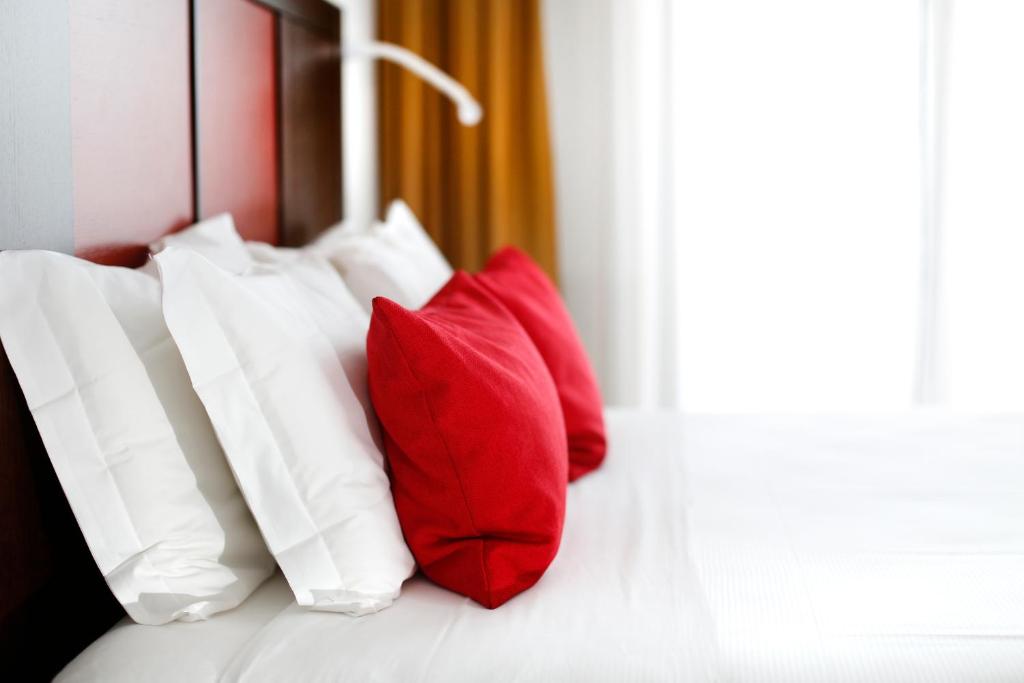 Hotel Holiday La Marca في فيلّوربا: مجموعة من الوسائد الحمراء والبيضاء على السرير