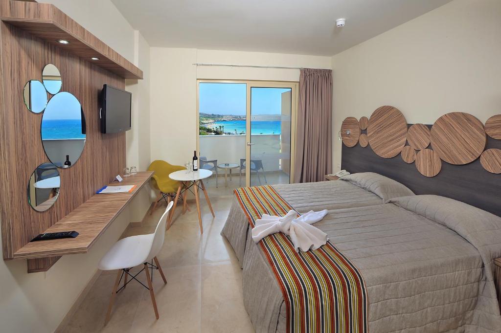 a hotel room with a bed and a desk and a television at Nelia Beach Hotel & Spa in Ayia Napa