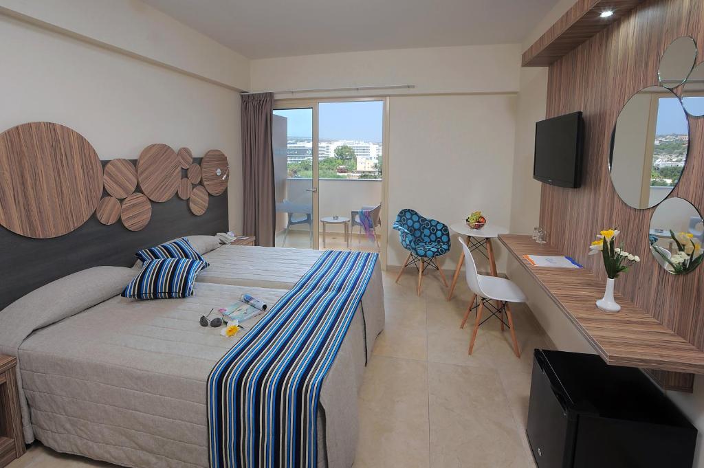 a bedroom with a bed and a desk and a television at Nelia Beach Hotel & Spa in Ayia Napa