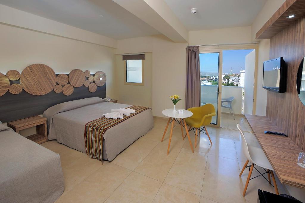 a bedroom with a bed and a table and a television at Nelia Beach Hotel & Spa in Ayia Napa
