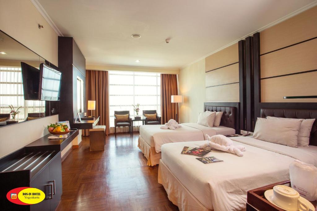 Habitación de hotel con 2 camas y TV en Ros-In Hotel, en Yogyakarta