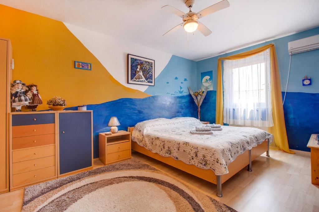 ein Schlafzimmer mit einem Bett und einer gelb-blauen Wand in der Unterkunft Apartment Simpatico in Čunski
