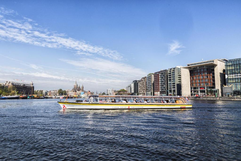 a boat filled with people on a river with buildings at Felicitas in Amsterdam